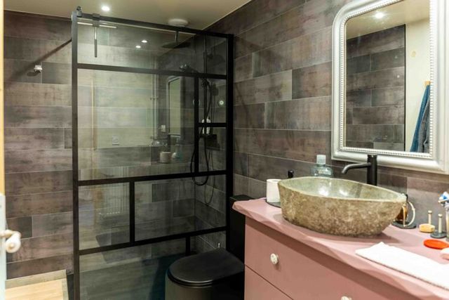 Salle de bain avec douche, carrelage et lavabo.